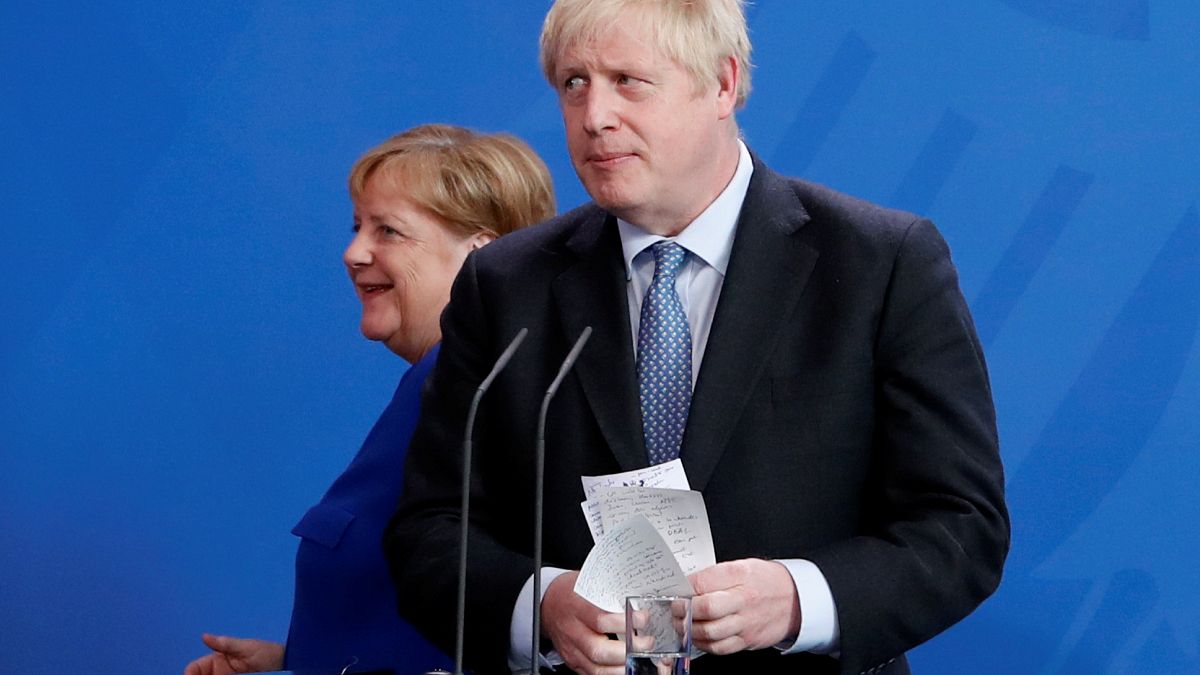 El Primer Ministro de Gran Bretaña, Boris Johnson, sostiene sus notas mientras asiste a una conferencia de prensa con la Canciller alemana Angela Merkel.