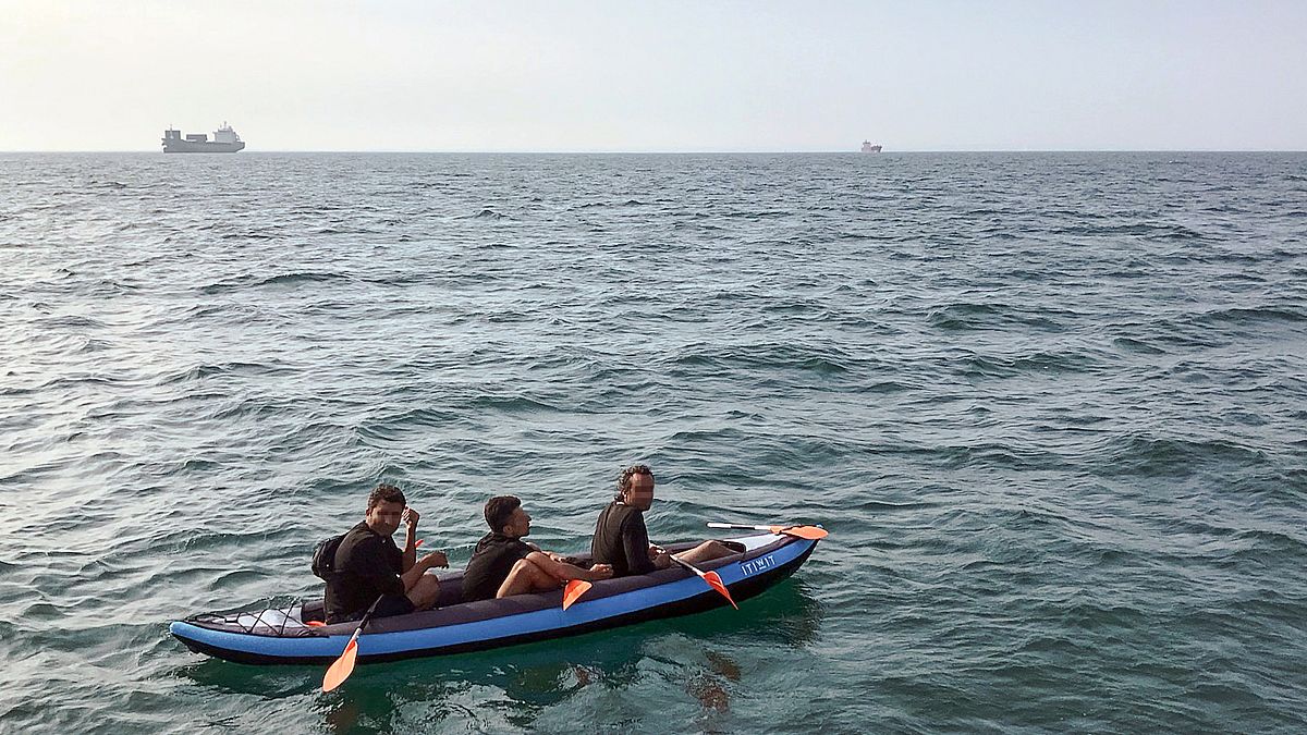 Three migrants who were attempting to cross The English Channel from France to Britain are seen as they drift in an inflatable canoe off the French coast at Calais on August 4