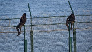 مهاجران من إفريقيا يحاولان عبور السياج الذي يفصل سبتة الإسبانية عن المغرب