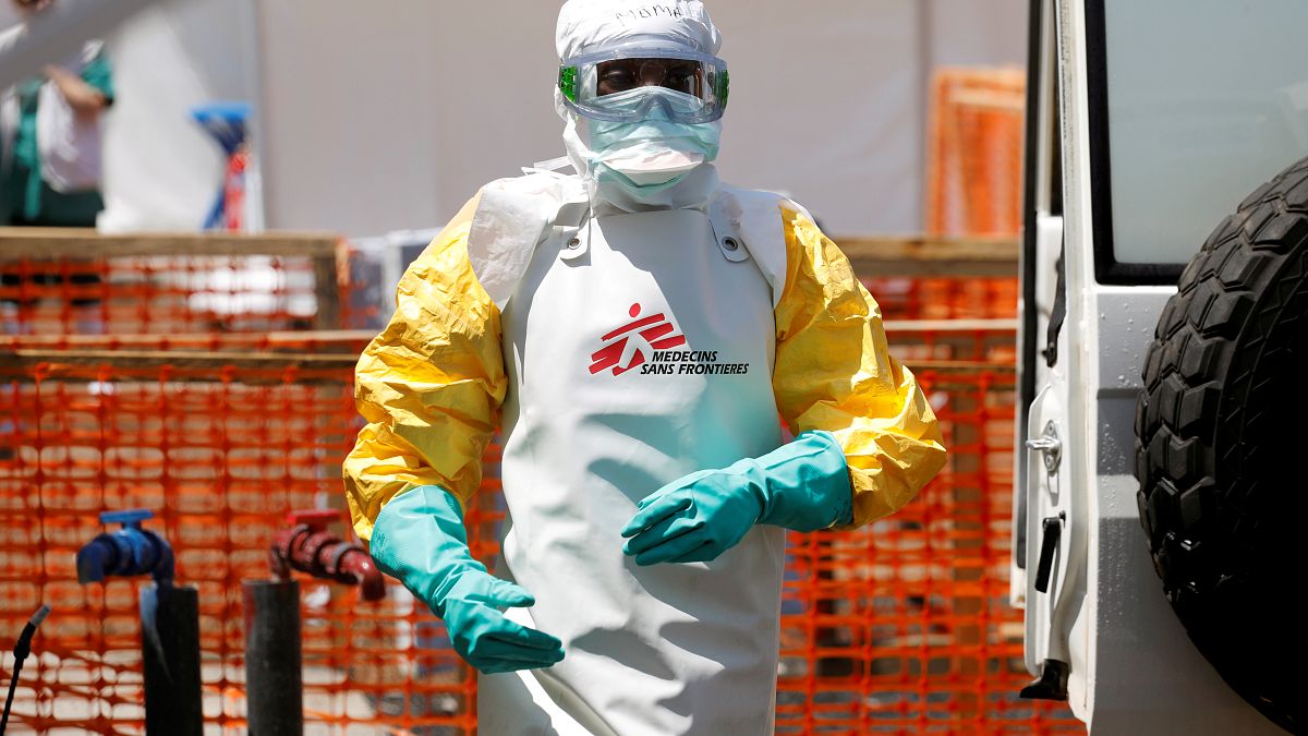 A health worker dressed in protective suit disinfects an ambulance transporting a suspected Ebola patient to the newly constructed MSF Ebola treatment centre in Goma