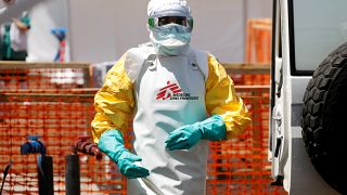 A health worker dressed in protective suit disinfects an ambulance transporting a suspected Ebola patient to the newly constructed MSF Ebola treatment centre in Goma