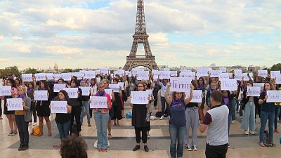 People write the names of women killed during a rally in Paris