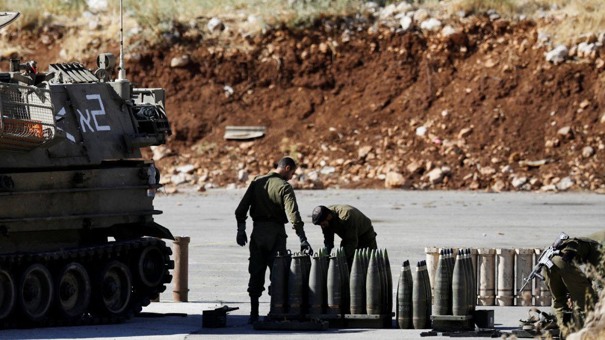 جنود إسرائيليون يقفون بجانب القذائف ووحدة مدفعية متحركة بالقرب من الجانب الإسرائيلي من الحدود مع سوريا- أرشيف رويترز