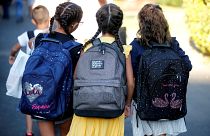 ثلاث تلميذات بانتظار الحافلة في مدينة مارسيليا الفرنسية للالتحاق بأول يوم مدرسي