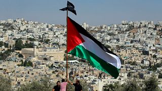 متظاهرون يرفعون العلم الفلسطيني خلال احتجاج على الزيارة المزمعة لرئيس الوزراء الإسرائيلي نتنياهو إلى مدينة الخليل في الضفة الغربية