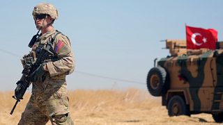 جندي تابع للقوات الأميركية أمام آلية للجيش التركي في الشمال السوري
