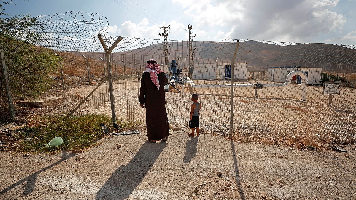 فلسطينيون يقفون إلى جانب السياج في وادي الأردن في الضفة الغربية المحتلة