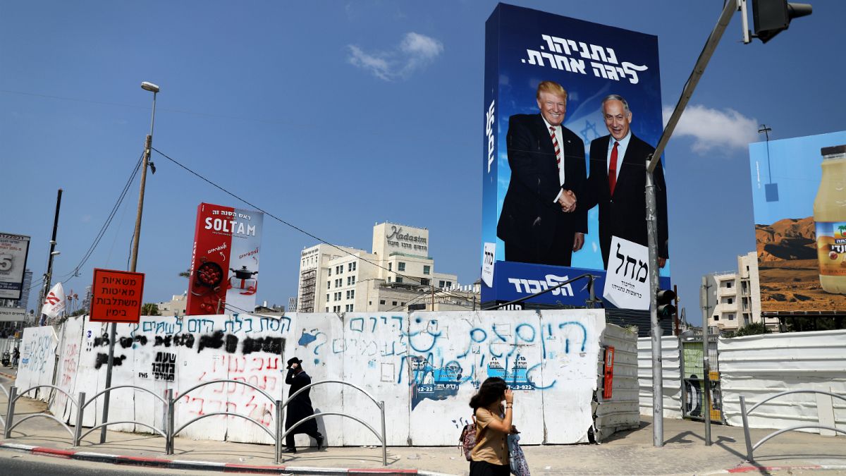 مشاة يسيرون بجانب لافتة لحملة حزب الليكود الانتخابية تصور رئيس الوزراء الإسرائيلي بنيامين نتنياهو والرئيس الأمريكي دونالد ترامب في بني براك، إسرائيل