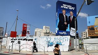 مشاة يسيرون بجانب لافتة لحملة حزب الليكود الانتخابية تصور رئيس الوزراء الإسرائيلي بنيامين نتنياهو والرئيس الأمريكي دونالد ترامب في بني براك، إسرائيل