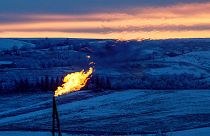 A natural gas flare on an oil well pad burns as the sun sets outside Watford City, North Dakota