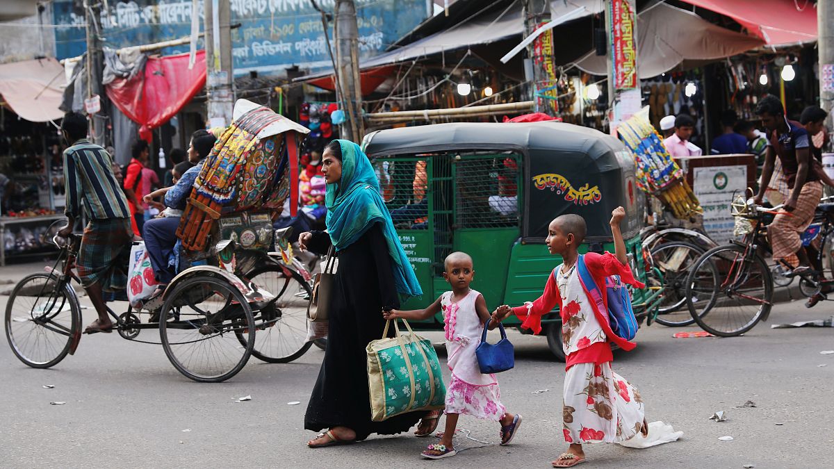 امرأة مع أطفال تعبر طريقًا في دكا-بنغلاديش