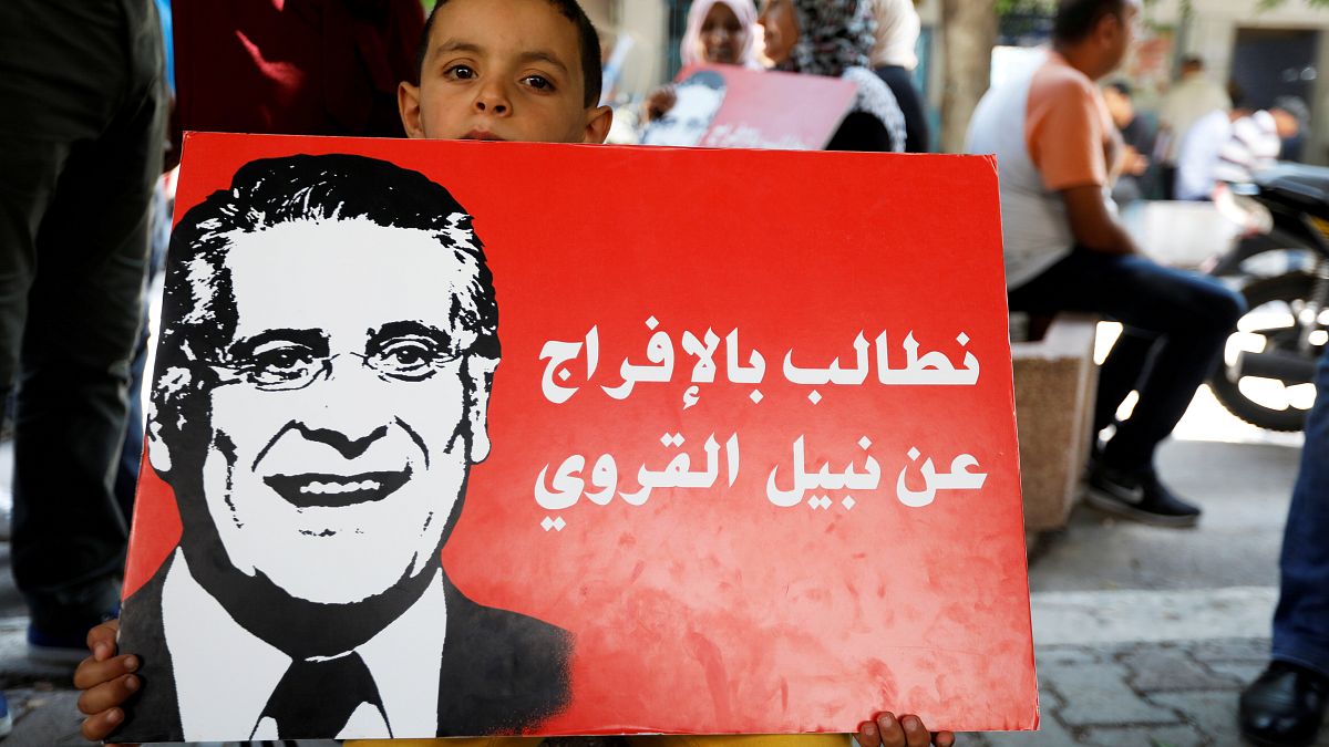A boy holds a picture of presidential candidate Nabil Karoui as he takes part in a rally asking for his release from prison, in front of the courthouse in Tunis, Tunisia,