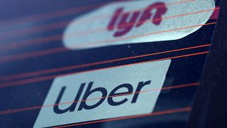 Uber and Lyft signs are seen on a car in Redondo Beach