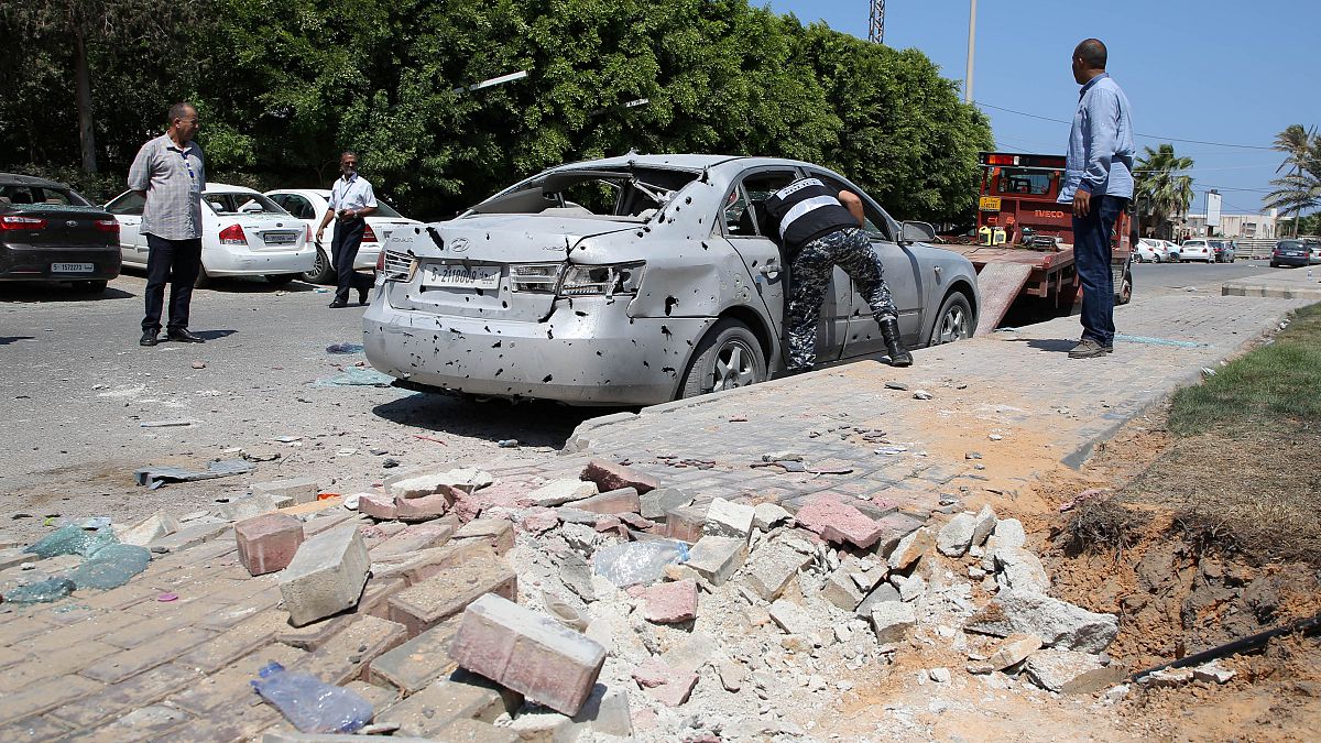 شرطي يعاين سيارة تعرضت لشظايا قصف استهدف مطار معيتيقة يوم 2019/08/24. حازم أحمد - رويترز