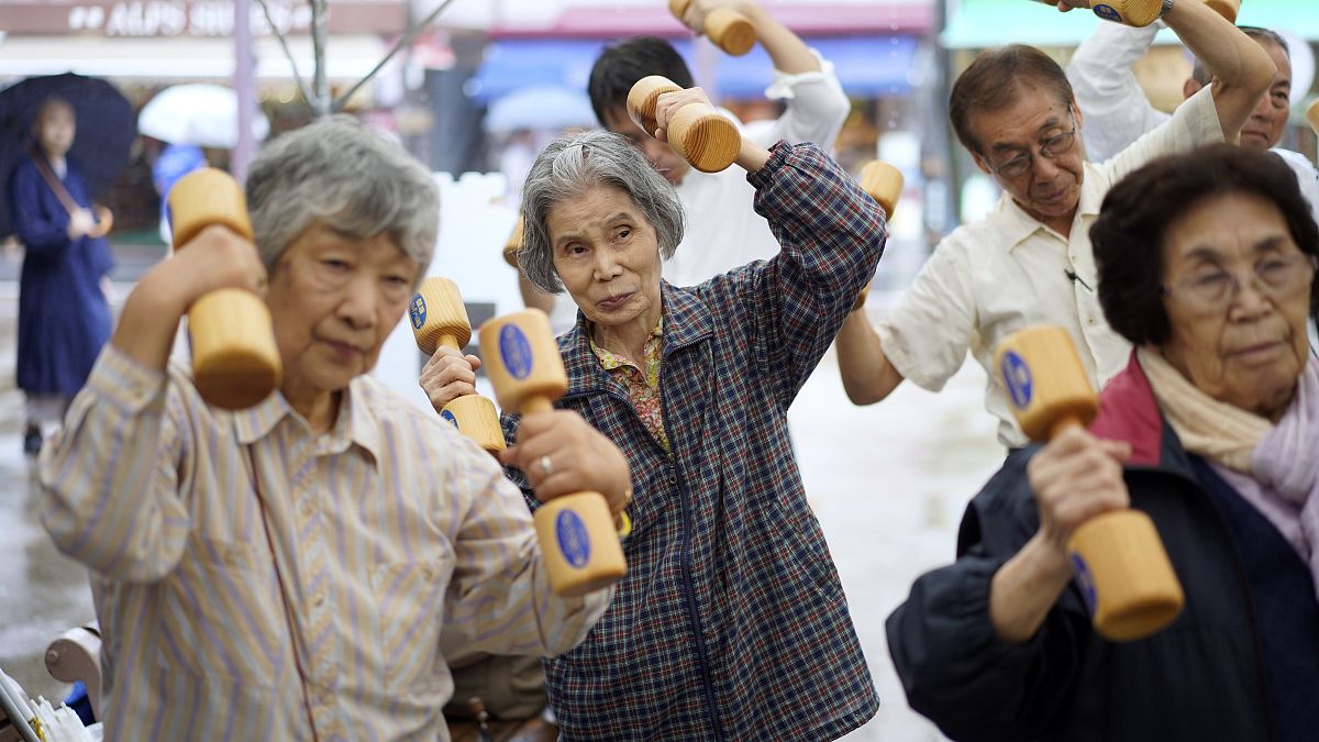 Idős japánok fa súlyzókkal tornáznak az idősek tiszteletének országos napján tartott köztéri rendezvények egyikén Tokióban 2019. szeptember 16-án