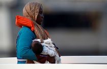 مهاجرة تحمل رضيعاً خلال وصولها إلى أحد موانئ مالطا بعد إنقاذها من قبل القوات البحرية