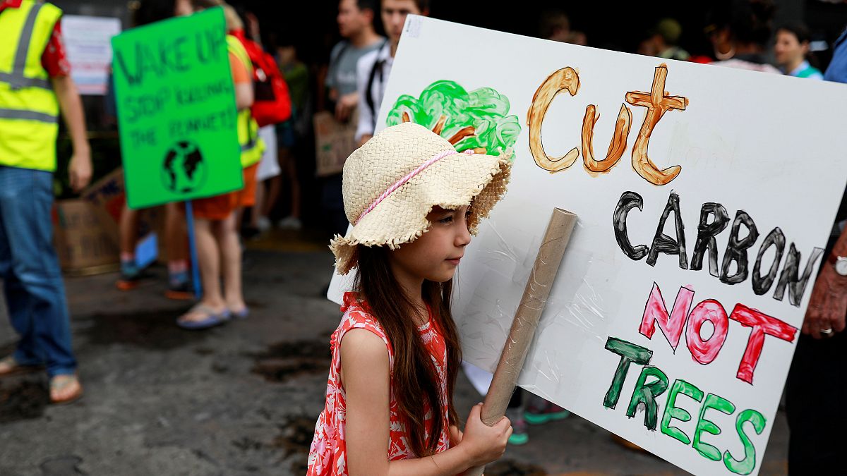 Corten el CO2, no los árboles, dice el cartel de esta niña en Tailandia