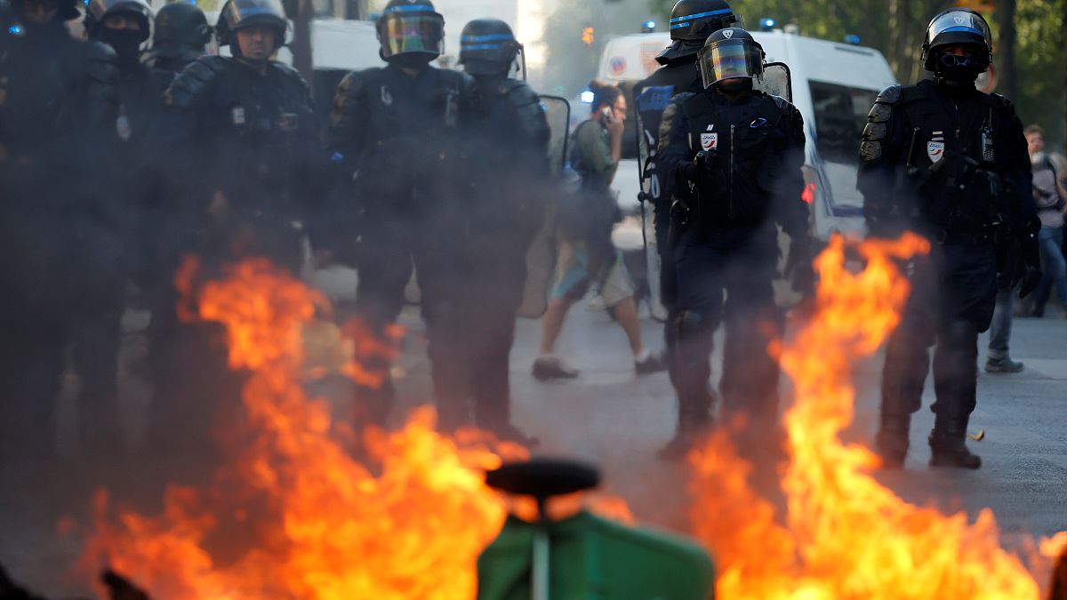 Riot police officers stand next to a burning barricade during a protest urging authorities to take emergency measures against climate change, in Paris, France.