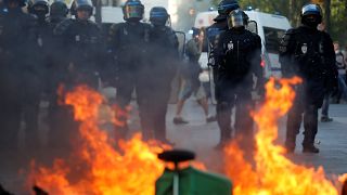 Riot police officers stand next to a burning barricade during a protest urging authorities to take emergency measures against climate change, in Paris, France.