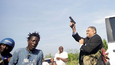 Senator Jean Marie Ralph Féthière (r.) schießt mit einer Pistole. 