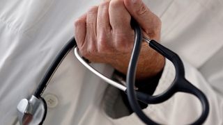 FILE PHOTO: A photo illustration shows a French general practitioner holding a stethoscope in a doctor's office in Bordeaux