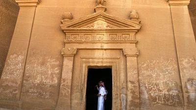 A tour guide stands inside a tomb at Madain Saleh
