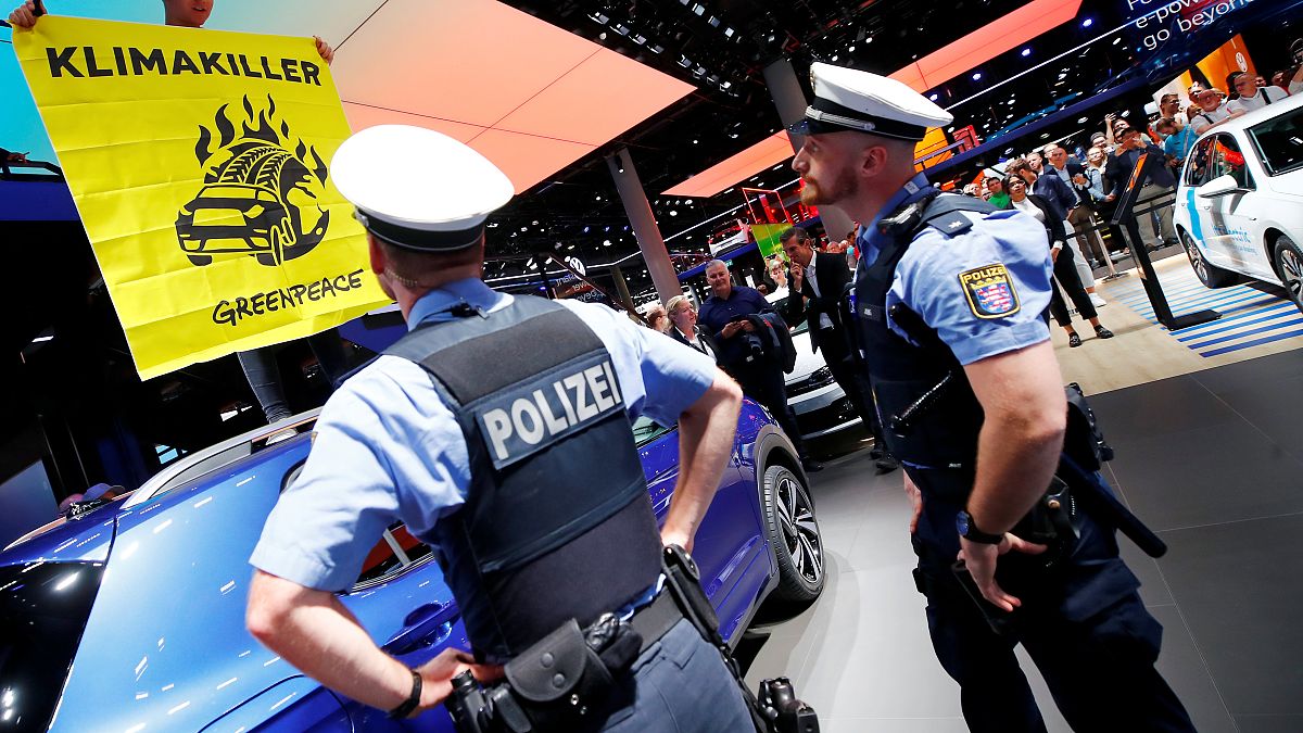 Greenpeace activist climbs on a displayed car as a sign of protest against the global warming during the visit of German Chancellor Angela Merkel to the Frankfurk Motor Show
