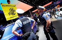 Greenpeace activist climbs on a displayed car as a sign of protest against the global warming during the visit of German Chancellor Angela Merkel to the Frankfurk Motor Show