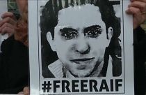 محتج يرفع ملصقاً مطالباً بإطلاق سراح المدون السعودي المسجون رائف بدوي