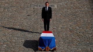French President Emmanuel Macron stands in front of the flag-draped coffin of late French President Jacques Chirac during a military funeral honors ceremony