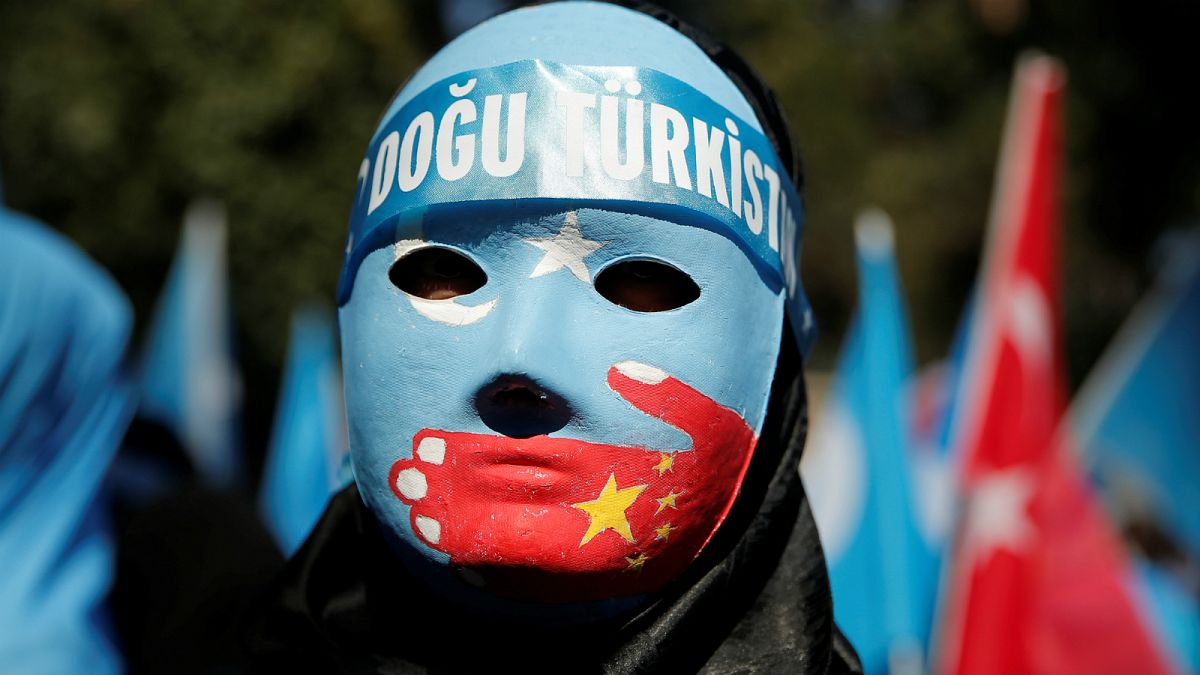 متظاهر يرتدي قناعًا يمثل أقلية الإيغور - أرشيف رويترز