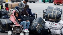 فتاة تجلس في عربة أطفال بينما ينتظر اللاجئون والمهاجرون نقلهم إلى مخيمات في ميناء بيرايوس في اليونان