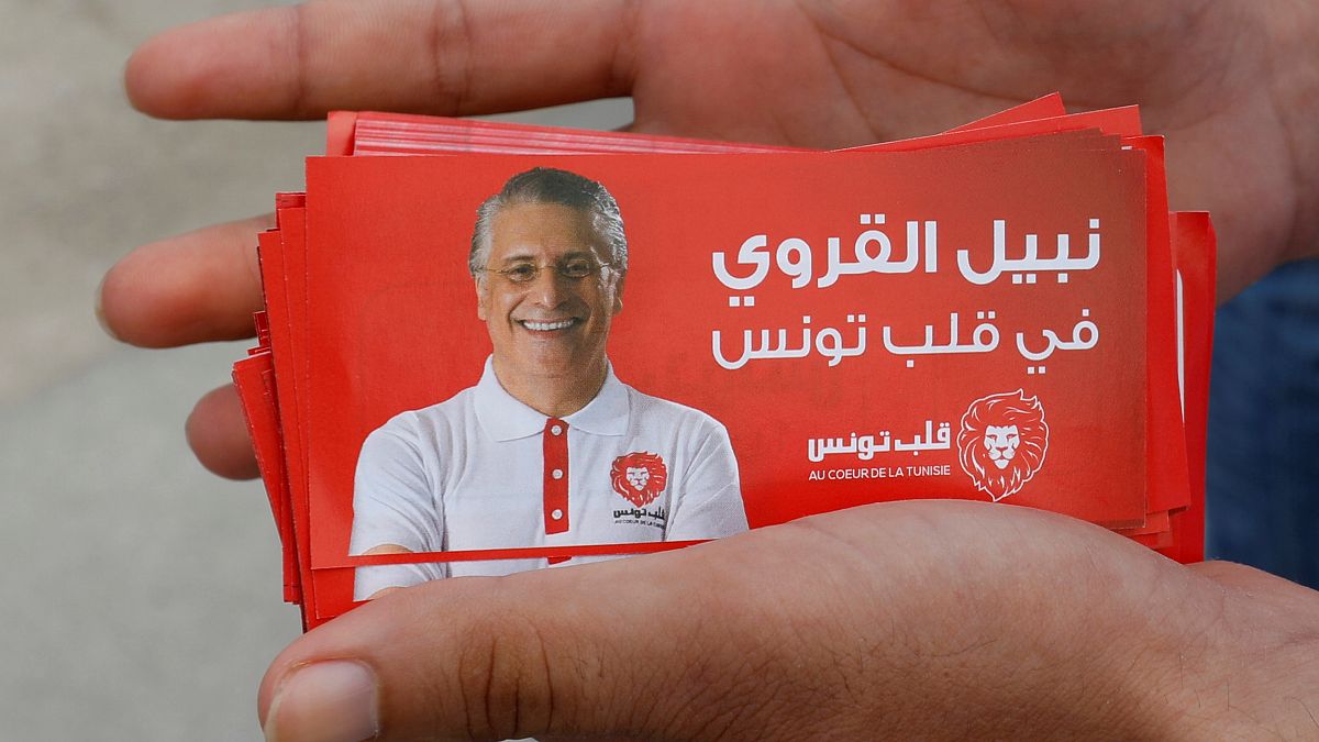 مواطن يحمل صور دعائية للمرشح الرئاسي التونسي نبيل القروي