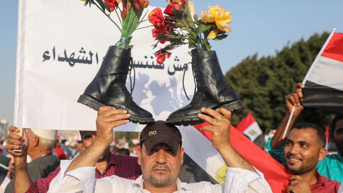 أحد أنصار الرئيس المصري عبد الفتاح السيسي يحمل أحذية عسكرية فوق رأسه وهو يهتف بالشعارات في القاهرة