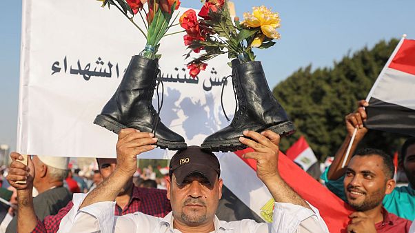 أحد أنصار الرئيس المصري عبد الفتاح السيسي يحمل أحذية عسكرية فوق رأسه وهو يهتف بالشعارات في القاهرة أحد أنصار الرئيس المصري عبد الفتاح السيسي يحمل أحذية عسكرية فوق رأسه وهو يهتف بالشعارات في القاهرة
