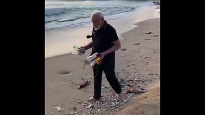 Modi da ejemplo y recoge plástico en la playa