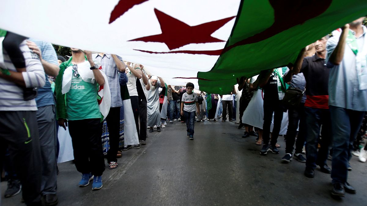 متظاهرون يحملون العلم الجزائري خلال احتجاج يوم 11 تشرين الأول/أكتوبر في العاصمة 