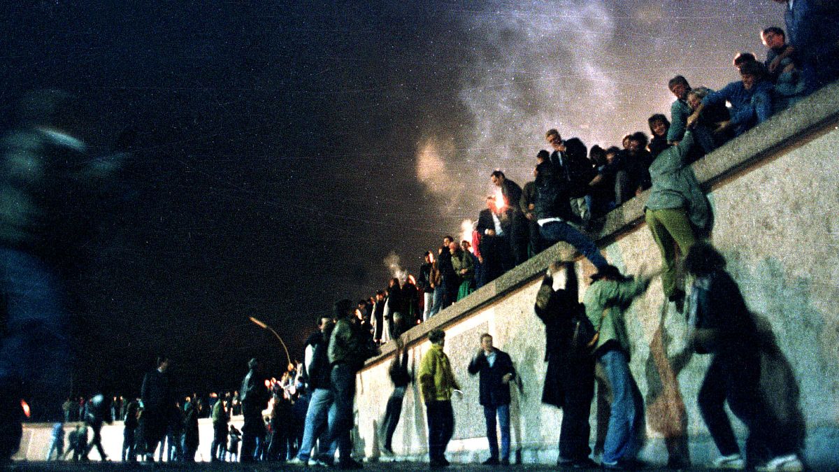 People climb the Berlin Wall at the Brandenburg Gate after the opening of the East German border November 9, 1989. 