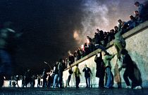 People climb the Berlin Wall at the Brandenburg Gate after the opening of the East German border November 9, 1989.
