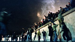 People climb the Berlin Wall at the Brandenburg Gate after the opening of the East German border November 9, 1989. 