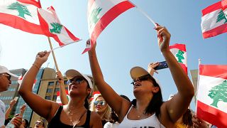 متظاهرتان لبنانيتان ترفعان العلم اللبناني في احتجاجت اليوم الثالث من الحراك الشعبي. 19/10/2019