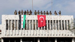 Türkiye sınırına yakın Suriye'nin Rasulayn şehrinde bir binanın üzerine Türk askerleri ve Suriye Milli Ordusu bayrak astı