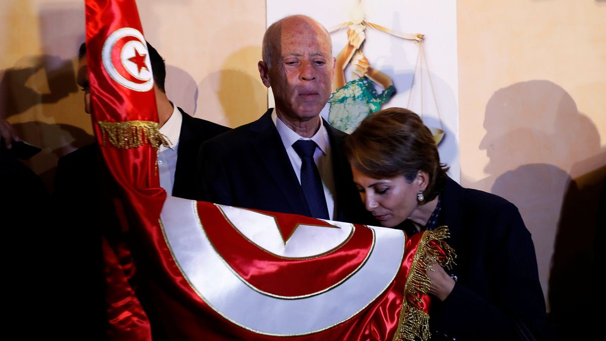قيس سعيد وزوجته أثناء تقبيلها للعلم التونسي