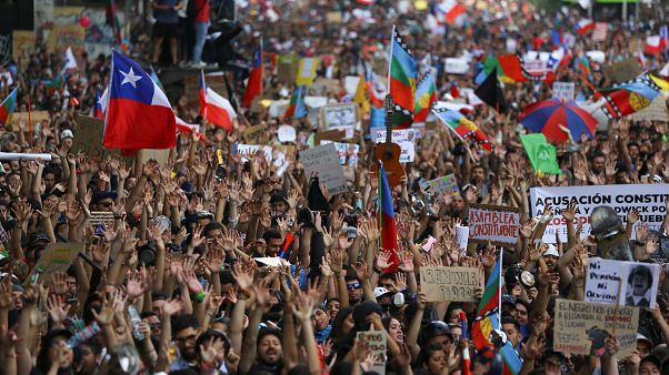 Manifestantes marchan con banderas y carteles durante una protesta contra el Gobierno de Sebastián Piñera en Santiago de Chile, Chile, el 25 de octubre de 2019. Manifestantes marchan con banderas y carteles durante una protesta contra el Gobierno de Sebastián Piñera en Santiago de Chile, Chile, el 25 de octubre de 2019.