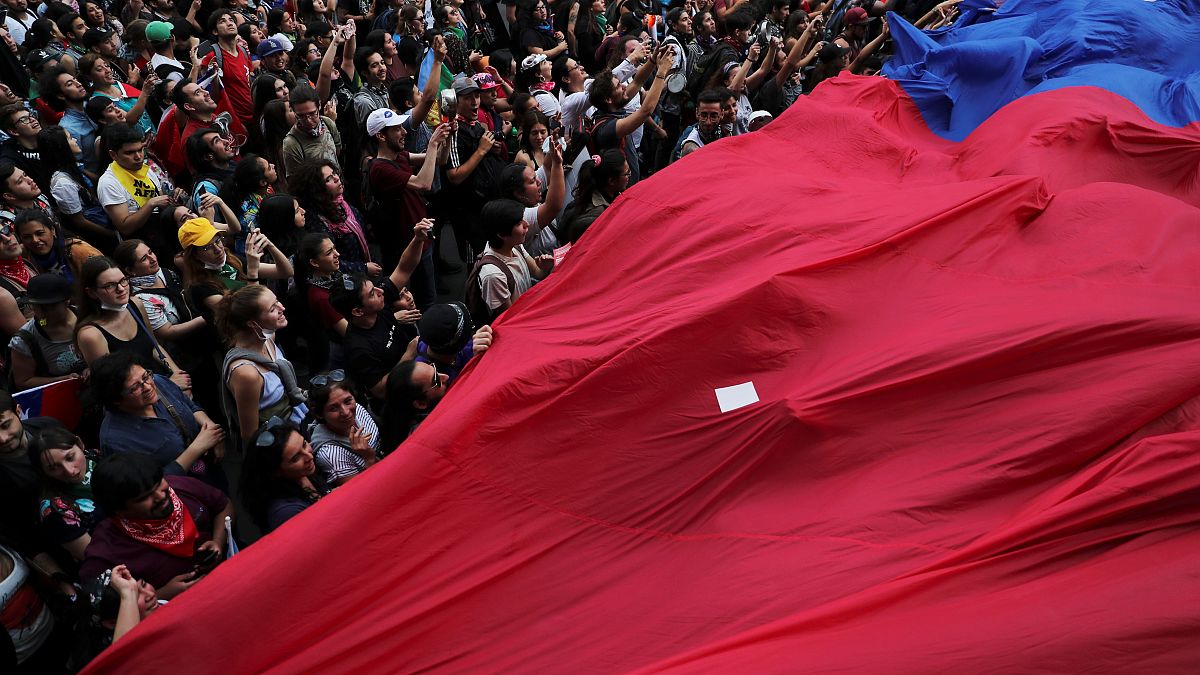 Demonstrators march with a giant flag during a protest against Chile's state economic model in Santiago, Chile October 25, 2019. 