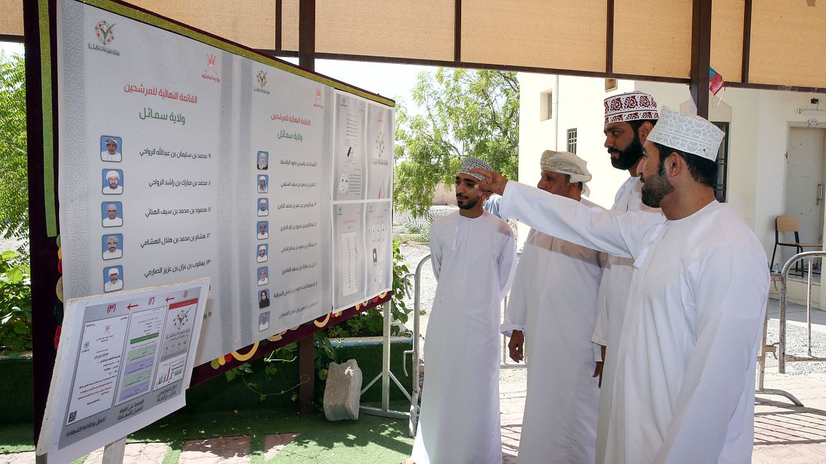 ناخبون بمدينة السمايل شمالي شرقي سلطنة عمان ينظرون إلى قوائم المرشحين لانتخابات مجلس الشورى. 27/10/2019