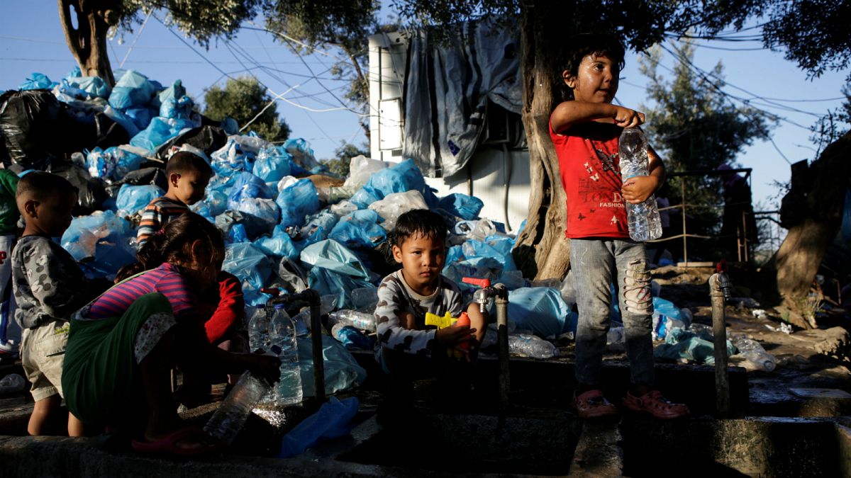 أطفال يملئون الزجاجات بالمياه بجوار مخيم موريا في جزيرة ليسبوس اليونان- أرشيف رويترز
