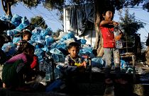 أطفال يملئون الزجاجات بالمياه بجوار مخيم موريا في جزيرة ليسبوس اليونان- أرشيف رويترز