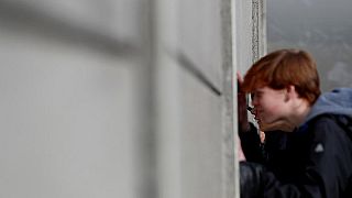 Besucher spicken durch die Mauer an der Gedenkstätte Berliner Mauer, Benauer Straße