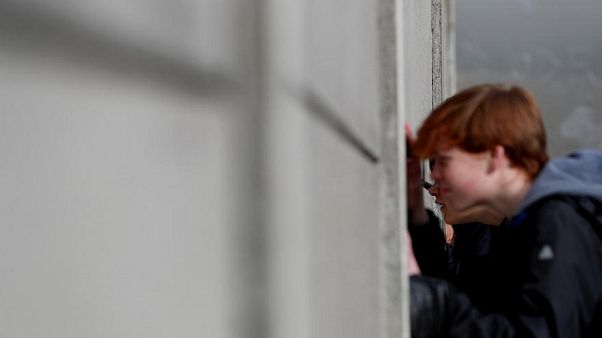 Besucher spicken durch die Mauer an der Gedenkstätte Berliner Mauer, Benauer Straße Besucher spicken durch die Mauer an der Gedenkstätte Berliner Mauer, Benauer Straße
